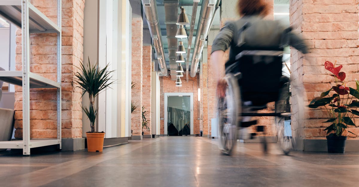Motion blur of a person in a wheelchair speeding through a modern office hallway with industrial decor.